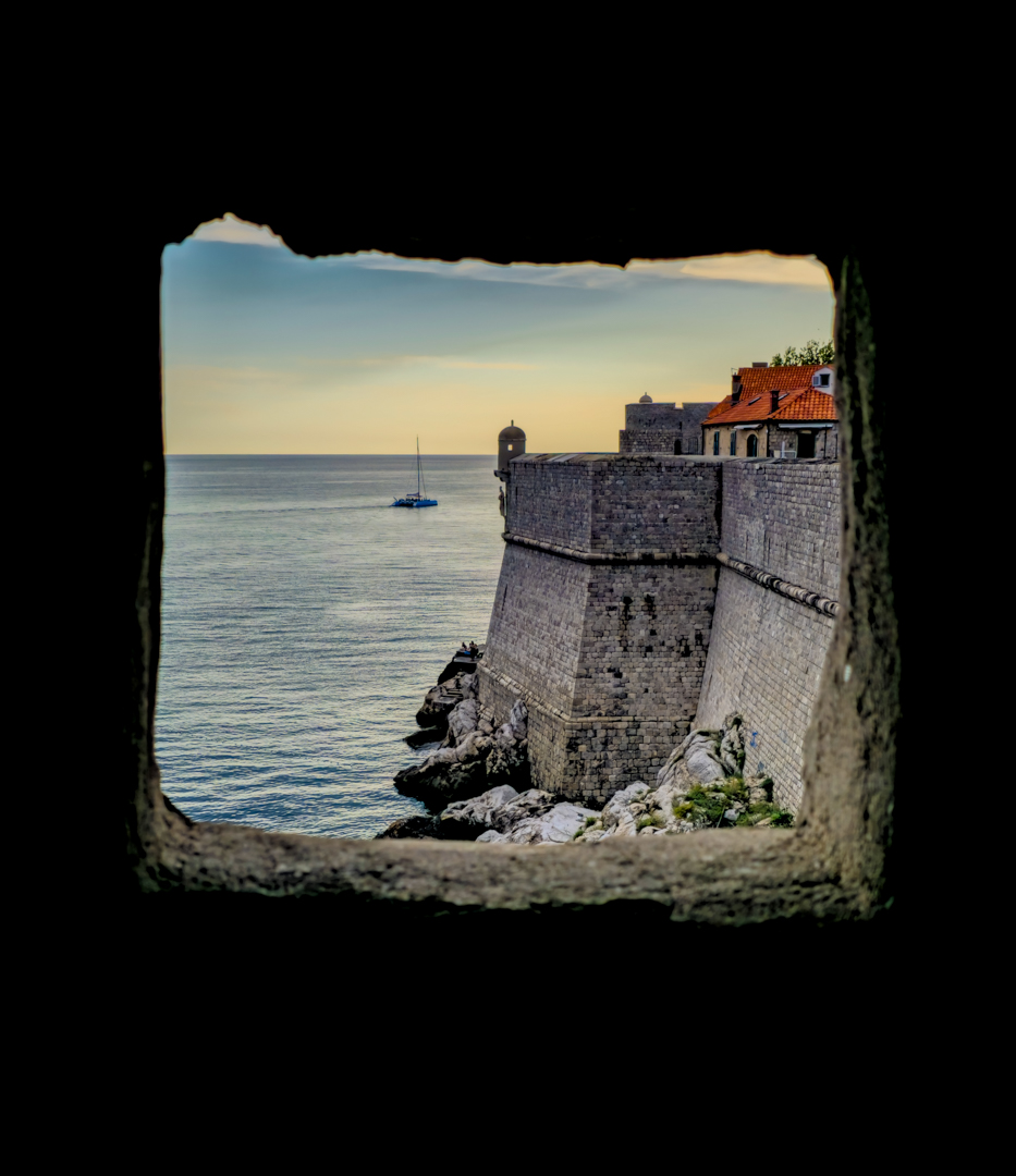 Outer Dubrovnik wall through a window, with a view of the statue.