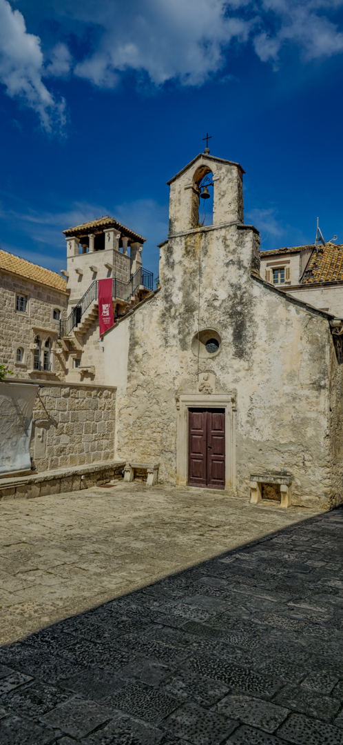 An old church in front of the tall tower of the Marco Polo Museum.